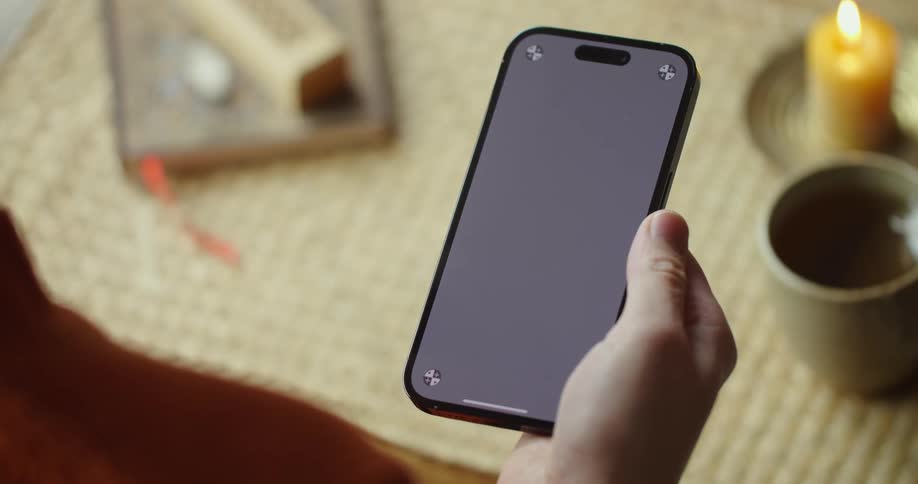 A man at a table at home scrolls on his cell phone