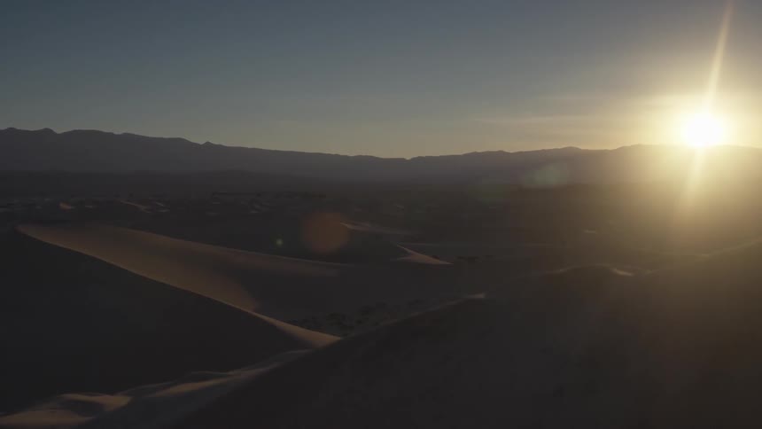 The sun is setting over the hills of this desert