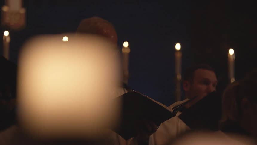 A choir sings in a candlelit church