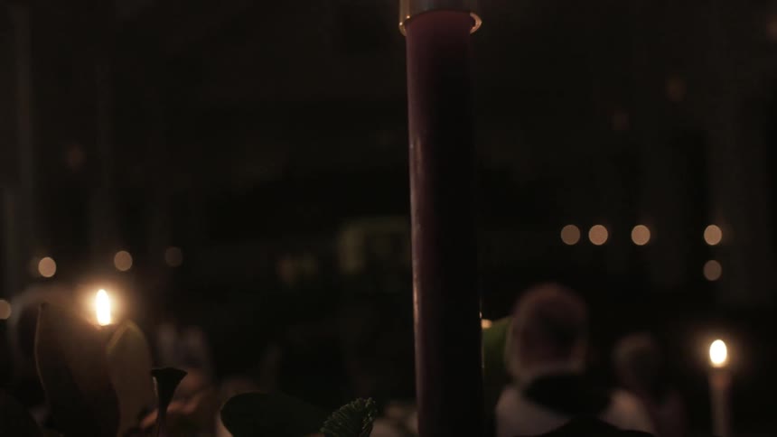 A church choir performs surrounded by candles