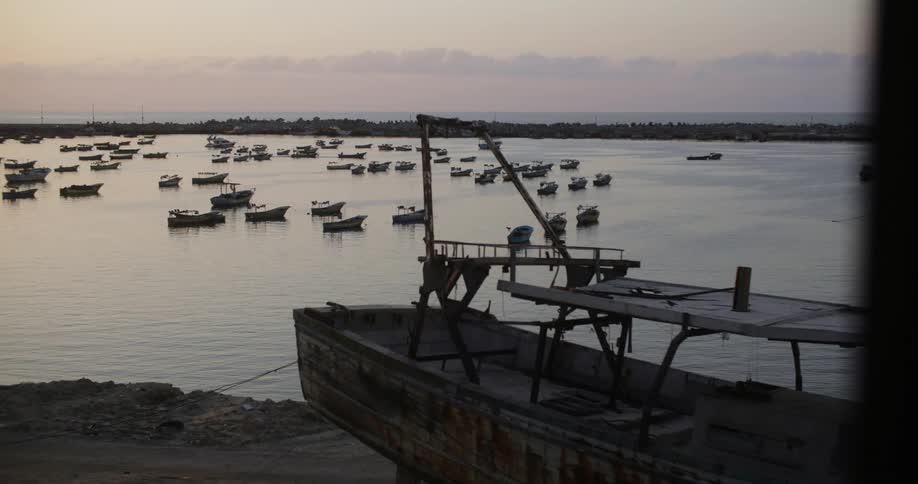 Dozens of small wooden boats sit parked in the sea