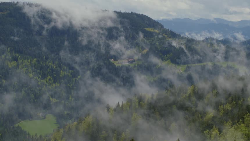 Aerial view of mountains covered in fog is displayed