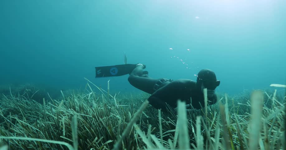 A diver signals with his fingers while exploring the ocean floor