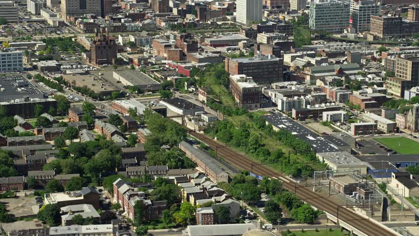Aerial footage showcasing North Phillys train tracks tilting up to reveal Philadelphias downtown skyline on a sunny day
