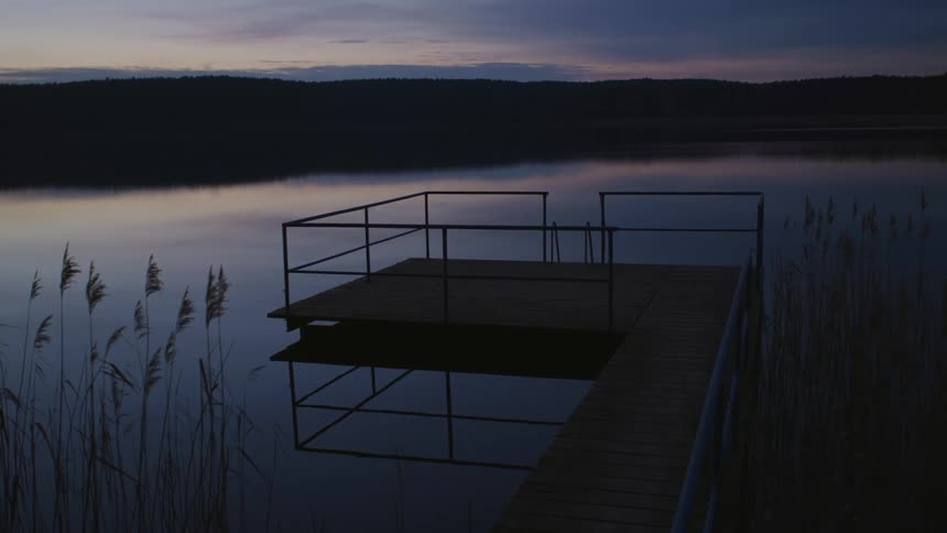 A dock is displayed on the lake at dusk