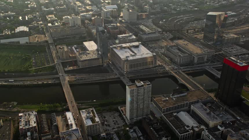 An evening aerial view of small bridges over Schuylkill River Main Post Office and 30th Street Station in Philadelphia Pennsylvania with a beautiful sunset in the backdrop