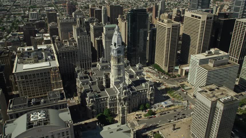An aerial footage of Philadelphias iconic city hall and the William Penn statue in downtown Philadelphia PA showcasing the citys historical and government landmarks shot during a sunny day