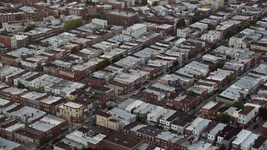 Aerial footage of an urban neighborhood in South Philadelphia at sunset tilting down to showcase the busy street below