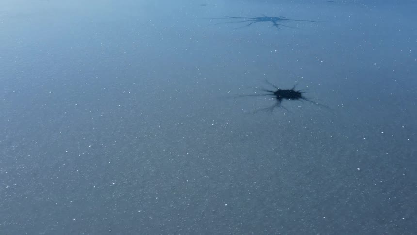 Hovering over a frozen body of water view of the ice frozen ice crystals on the surface and pockets of air under the ice