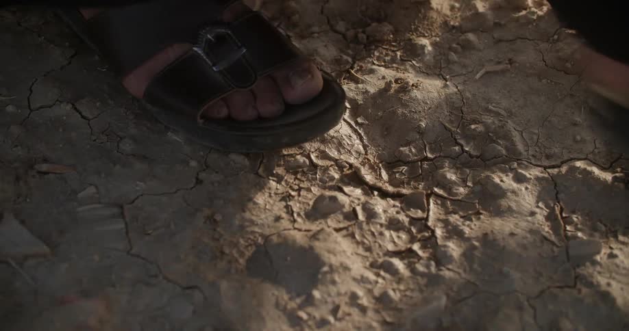 Walking across dirt path wearing open toed leather sandals