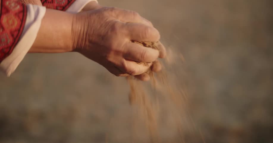 A person breaking apart dirt with their bare hands