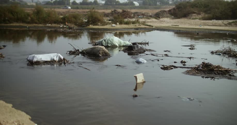 Trash and litter float in water a large distance from where car is parked
