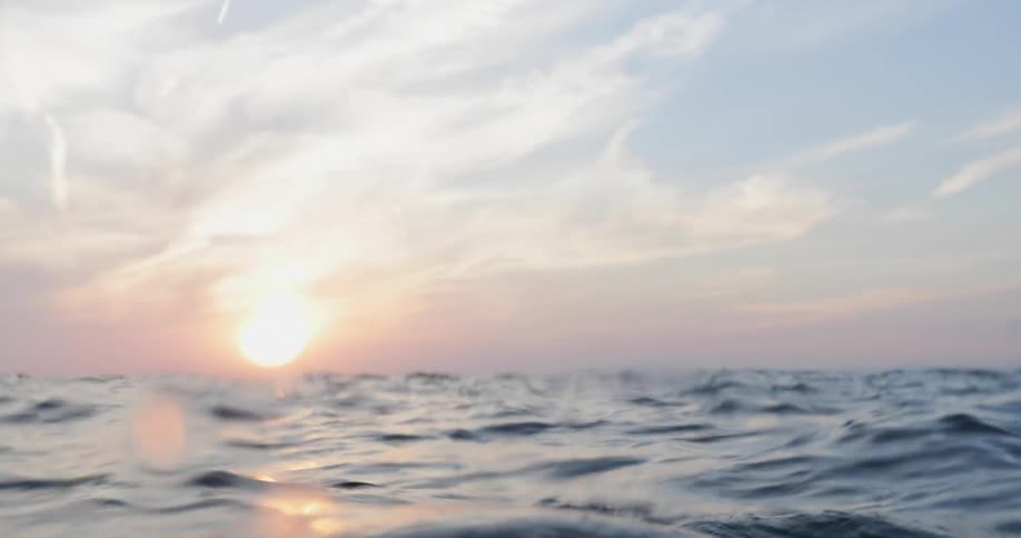A man is diving underwater while the sun is setting