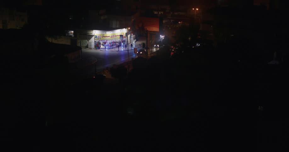 Cars are driving by a store in the suburbs at night
