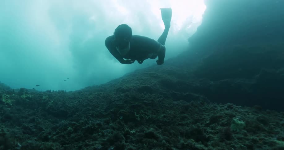 A person is diving under the ocean water