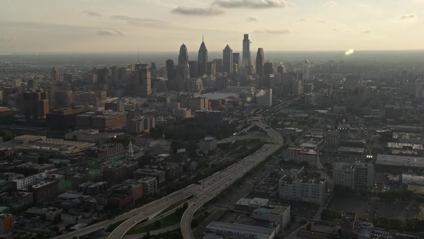 Aerial footage of Interstate 676 passing through downtown Philadelphias skyline during sunset