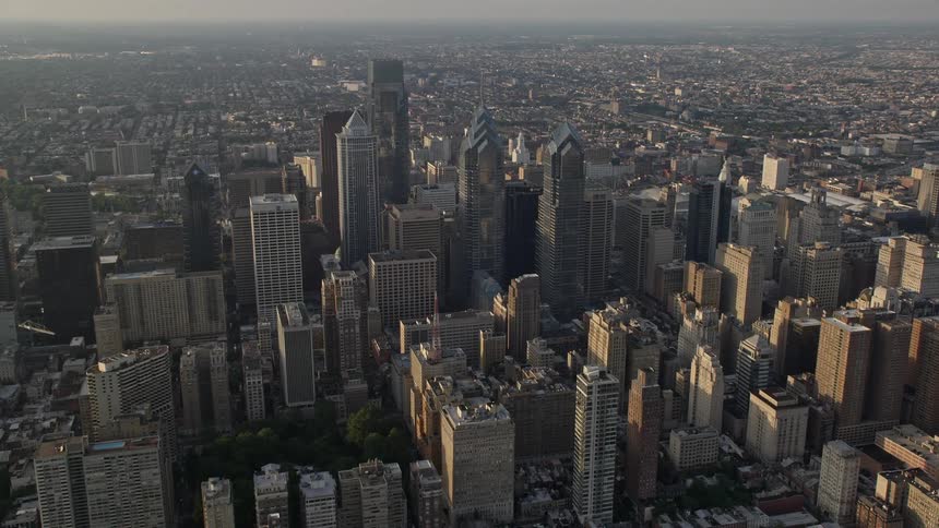 Aerial footage of Downtown Philadelphias skyscrapers city buildings and urban neighborhoods during sunset