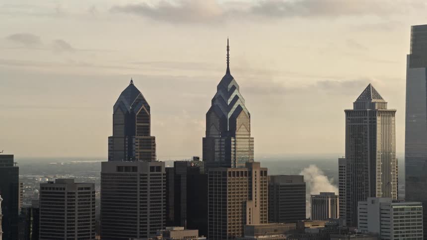 A stunning aerial view of the downtown Philadelphia skyline at sunset featuring the iconic One and Two Liberty Place high-rise buildings among other tall modern structures