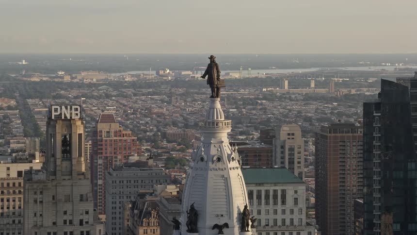 Approaching the iconic William Penn statue atop Philadelphia City Hall at dusk during sunset