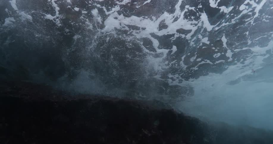 Waves flow over underwater shelf creating foam over the murky water