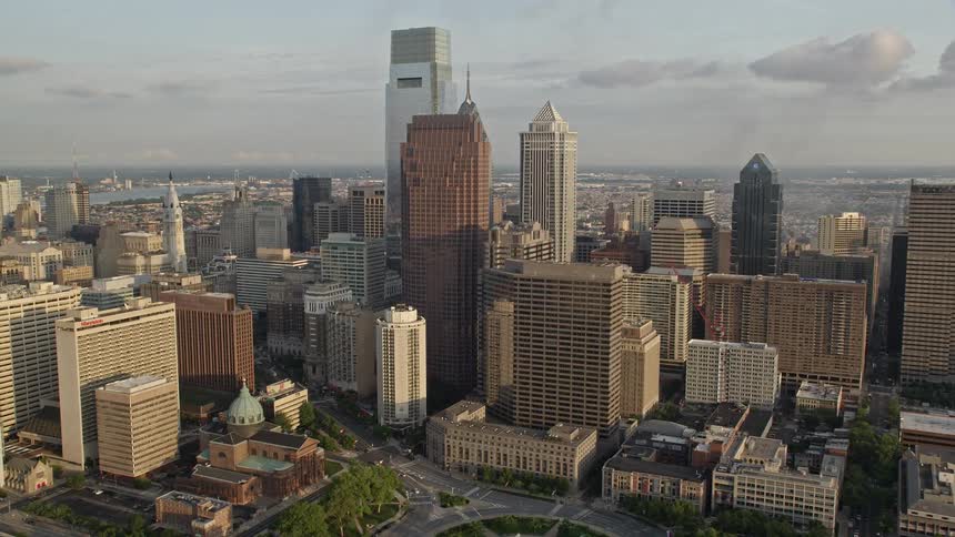 Aerial footage of Comcast Center BNY Mellon Center and Three Logan Square in downtown Philadelphia during sunset showcasing the citys modern high-rise buildings