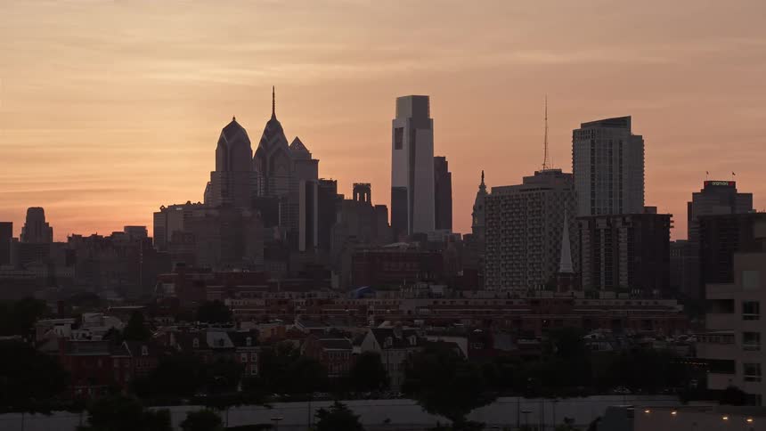Aerial footage of the Philadelphia skyline at sunset with a high-rise condo complex eclipsing the cityscape