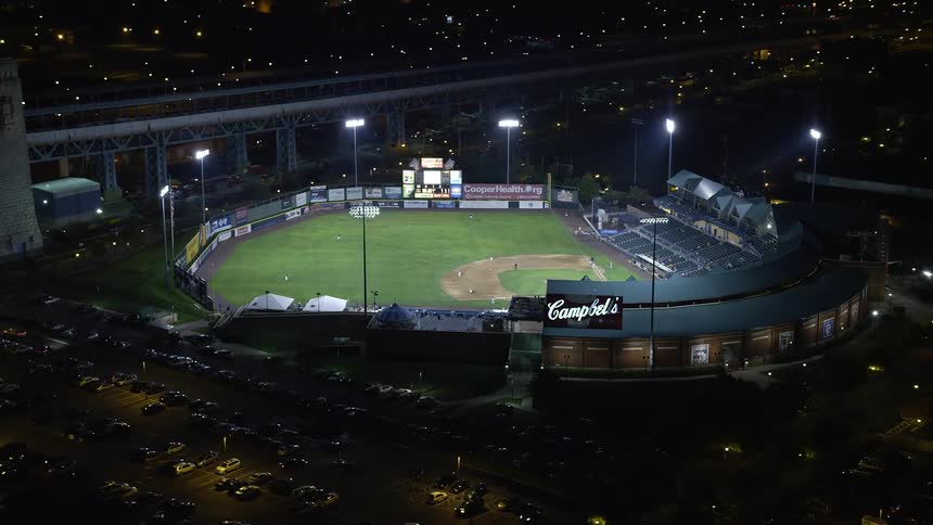 Aerial footage of a baseball game at Campbells Field in Camden New Jersey lit up at night with clear skies