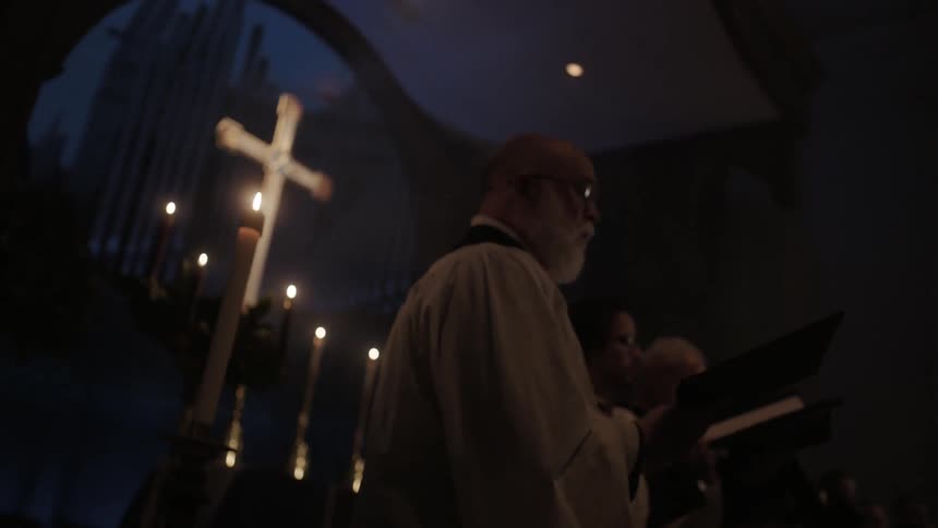 A church choir performs surrounded by candles and a cross