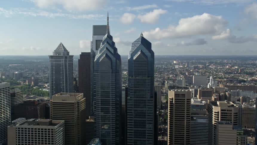 Aerial footage shows Philadelphias tallest towers and skyscrapers with stunning architecture towering over the bustling city below on a partly cloudy day