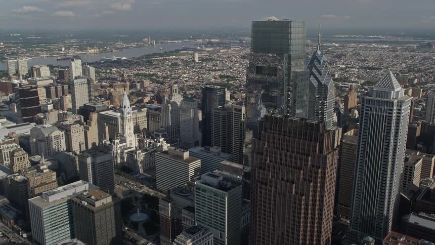 Aerial footage of Philadelphia City Hall and downtown skyscrapers during the day with partly cloudy skies