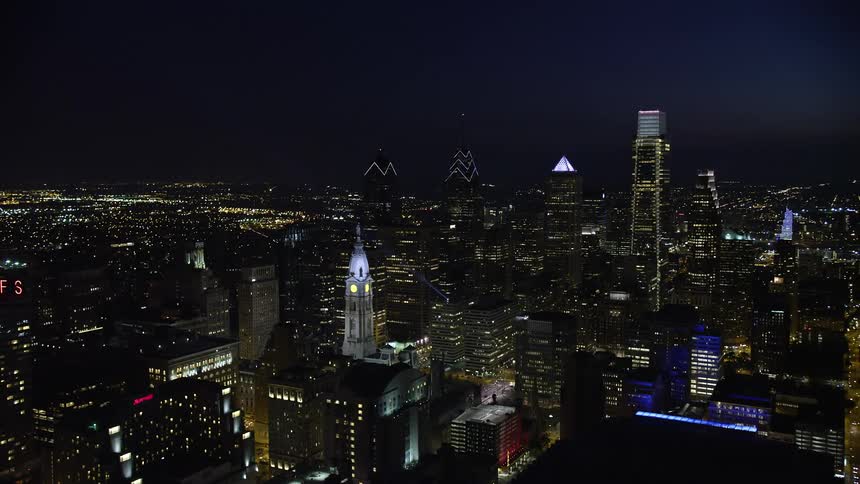 Aerial footage of Philadelphia City Hall and downtown skyscrapers at night as the camera flies away revealing the citys metropolis and iconic structures