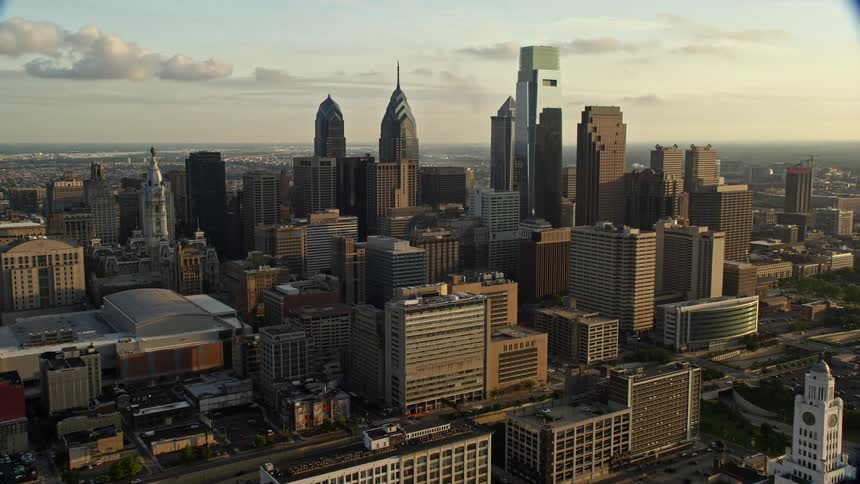 Approaching Philadelphias Downtown skyscrapers and high-rises at sunset from an aerial perspective