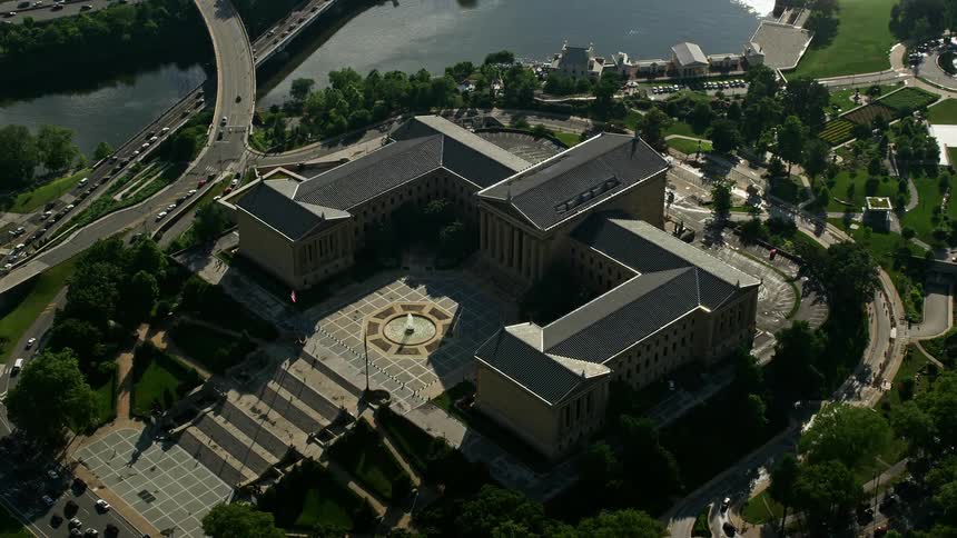 A stunning aerial view of the iconic Philadelphia Museum of Art set against a partly cloudy sky and the scenic Schuylkill River