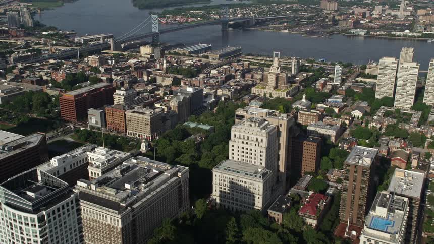 Aerial footage of apartment and office buildings around Washington Square and Independence National Historic Park in Downtown Philadelphia with a view of the Benjamin Franklin suspension bridge spanning the Delaware River