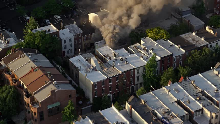 Aerial footage of thick smoke rising from a residential fire at sunset in the downtown area of Philadelphia Pennsylvania