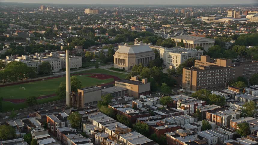 Sunset aerial footage of Girard College campus building in North Philadelphia Pennsylvania showcasing the industrial smoke stacks and clear skies