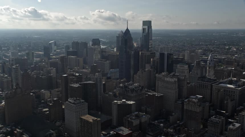 Aerial footage captures the approach to Downtown Philadelphias towering buildings in hazy midday weather