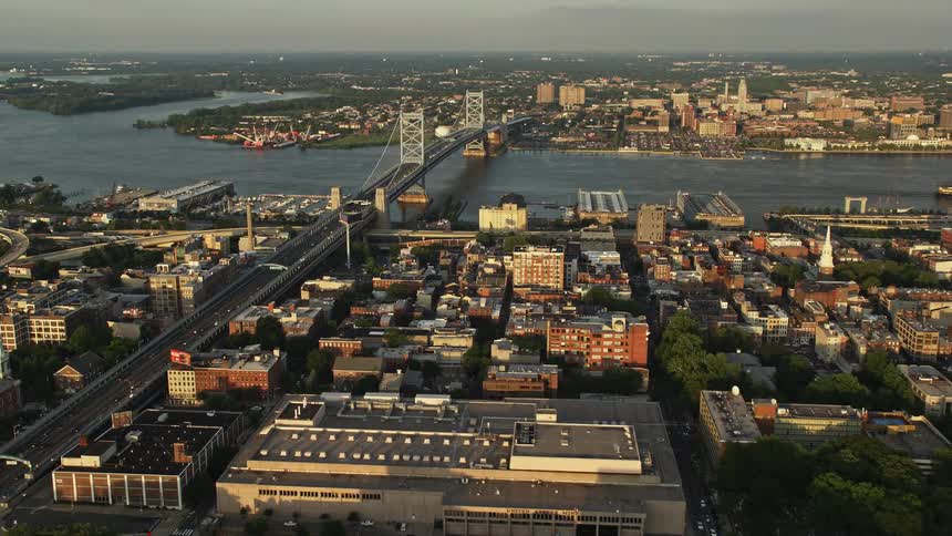 A stunning aerial view of Philadelphia at sunset capturing office buildings the Benjamin Franklin Bridge and the city skyline