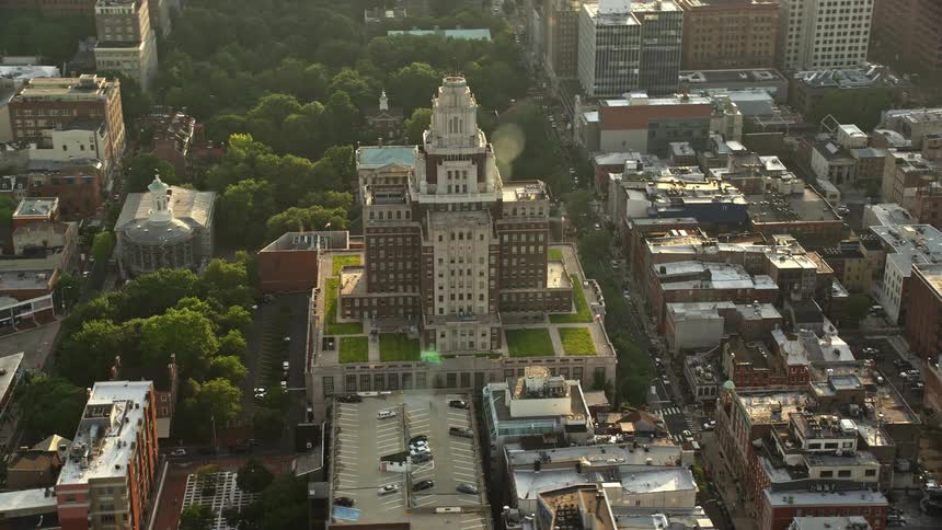 An iconic structure at the United States Customs House in Philadelphia is shown from a aerial perspective orbiting during a clear evening sunset with views of the citys downtown buildings during spring