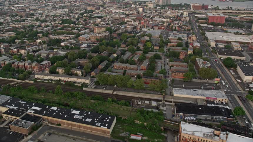 Aerial footage capturing row houses by railroad tracks and the Edgar Allan Poe House in North Philadelphia during sunset