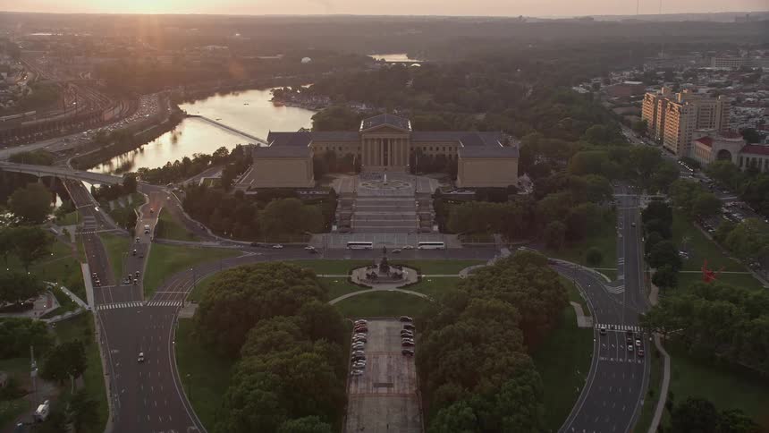Aerial footage capturing the sunset as the camera tilts up from Logan Square to reveal the iconic Philadelphia Museum of Art and the surrounding residential and downtown areas