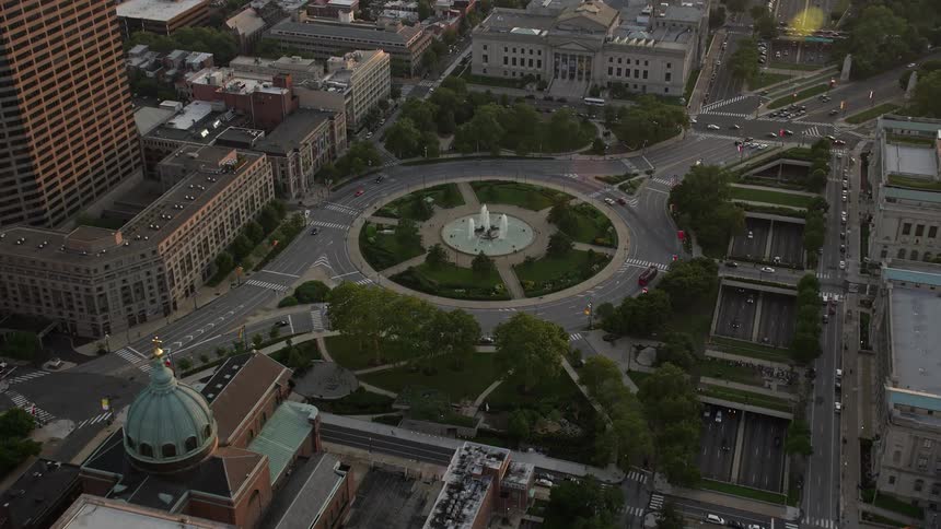 An aerial view of Logan Square in Downtown Philadelphia at sunset surrounded by towering office buildings and vehicles moving below