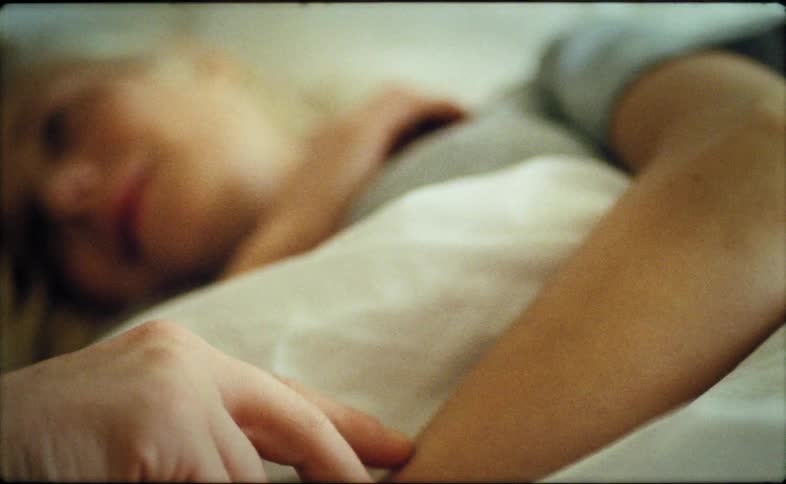 Man strokes arm of woman lying in bed