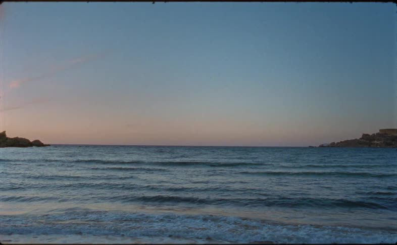 Sunlight shines on waves as they ripple and sparkle rolling into shore