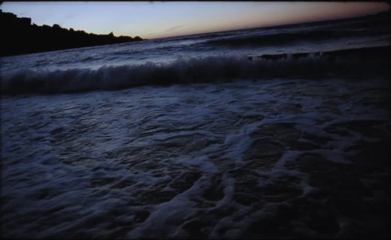 Ocean waves are moving towards the coast at dusk