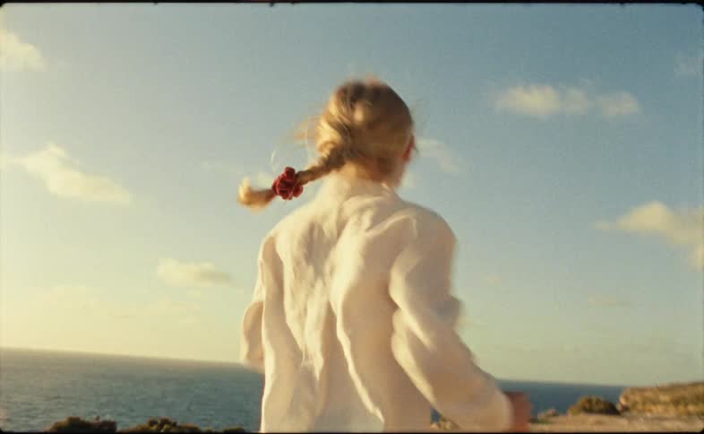 A woman runs along a cliff over the ocean