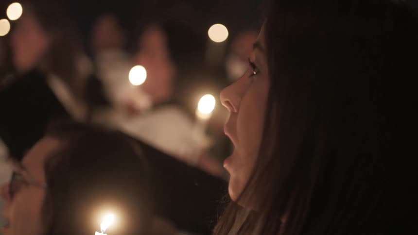 A church choir sings while holding candles