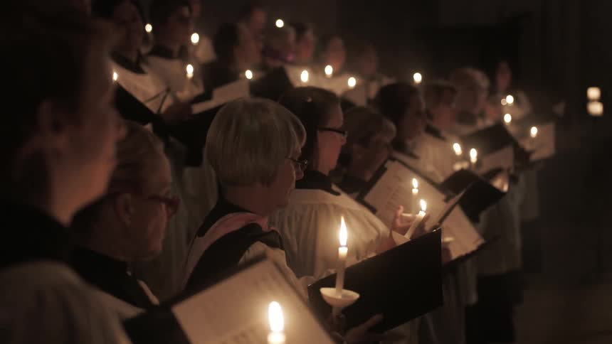 A church choir holding candles and singing