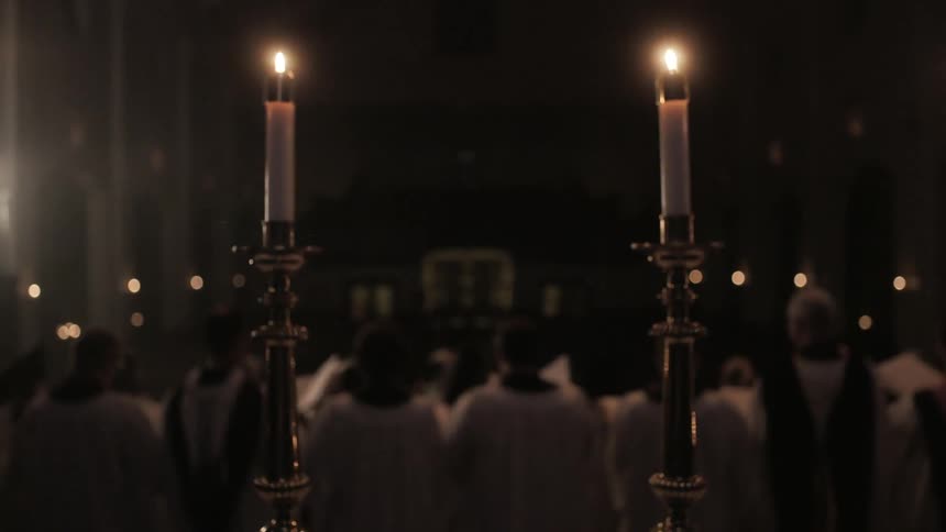 A choir sings in a candlelit church