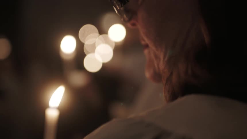 People are holding candles and books in a church